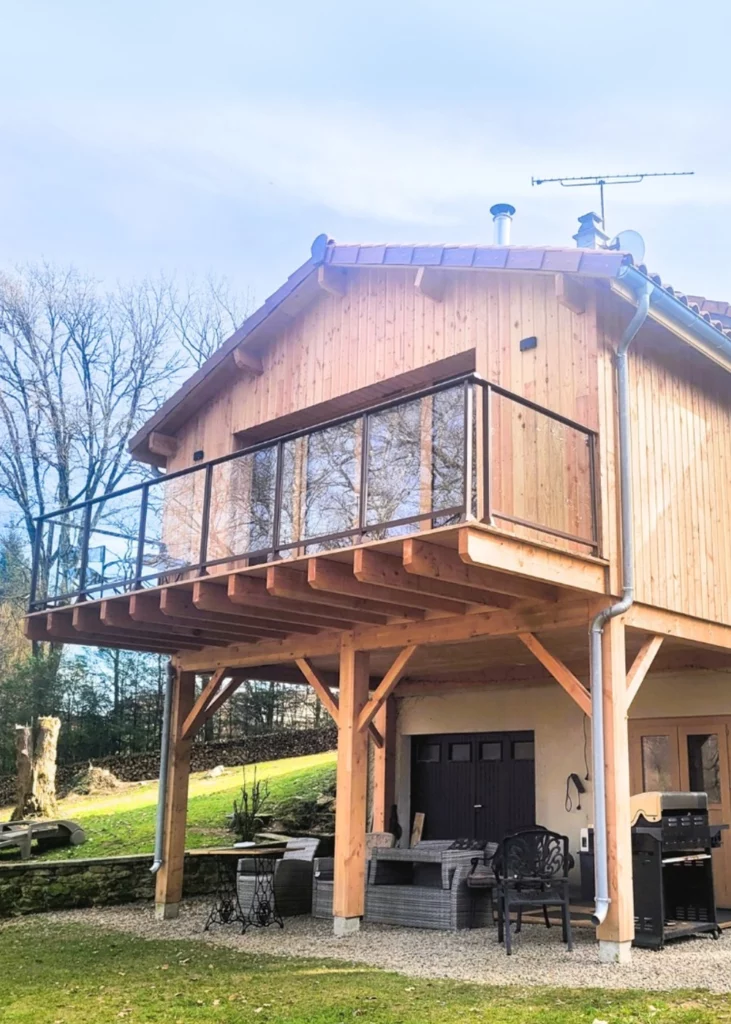 Agrandissement d'une maison en bois avec un garde-corps vitré.