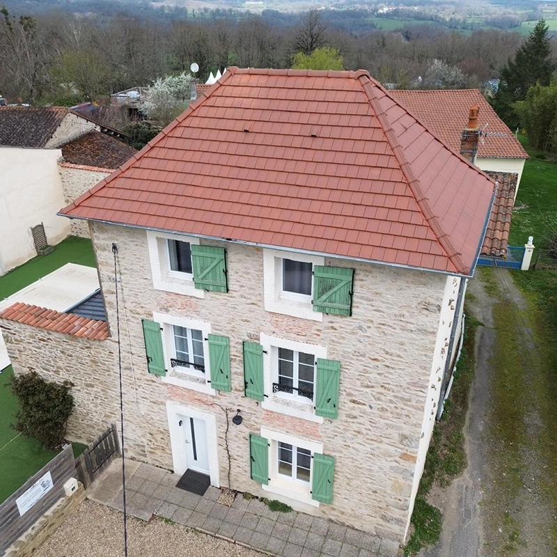 Maison en pierre avec des volets verts et une toiture en tuiles rénovée