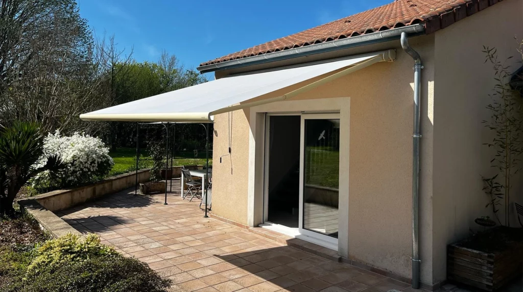 Une terrasse en pierre avec un store banne blanc à ouverture manuelle