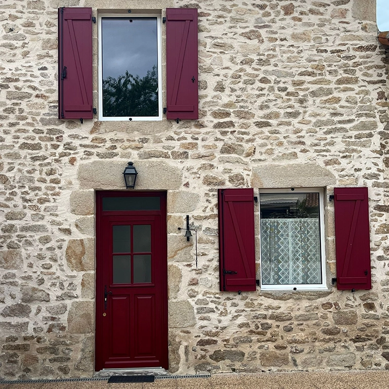 Volets traditionnels en bois, couleur bordeaux, assortie à la porte d'entrée